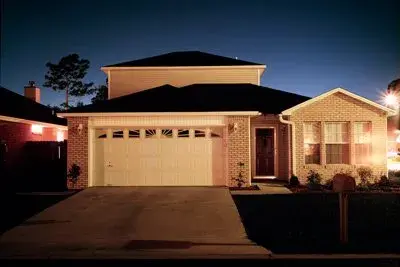 Brick home with a panelled sectional garage door at night